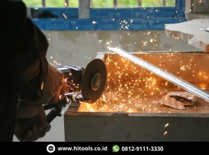 Mesin Gerinda Tangan Tips Memilih untuk Proyek Rumah dan Bengkel. 1 Mesin gerinda tangan memotong logam dengan percikan saat digunakan di workshop